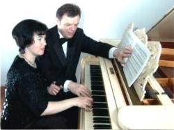 Antra and Normunds Viksne seen through the open lid of a grand piano